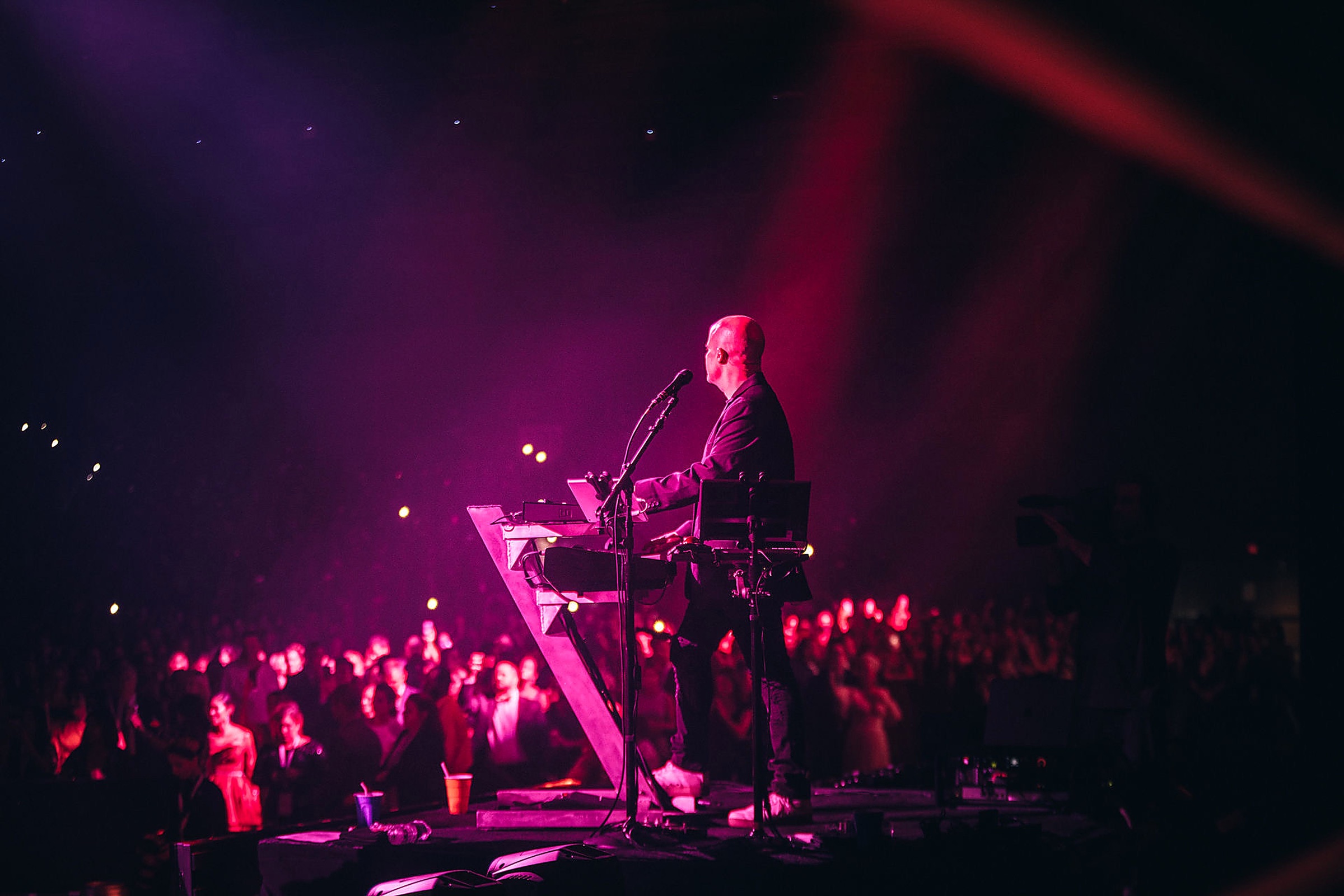 Jason Halbert at the keys on stage, lit in magenta, with a crowd beyond